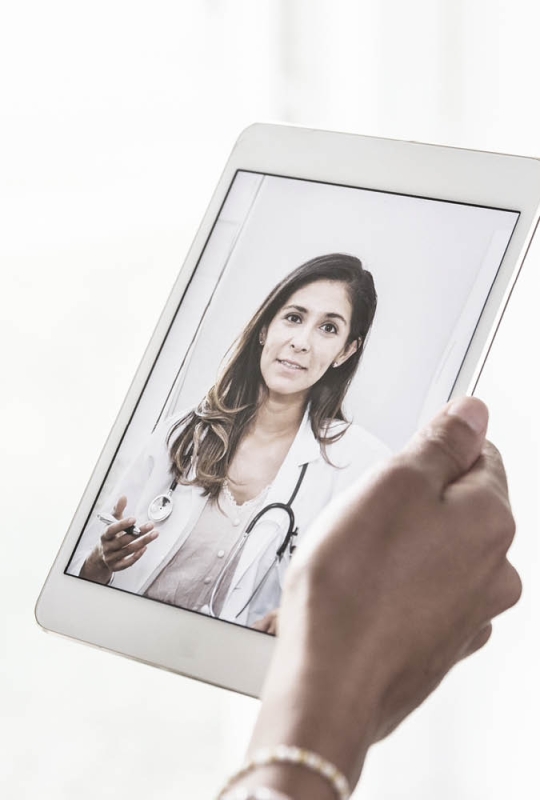 Een hand houdt een tabblad vast. Op het beeld is een dokter te zien.