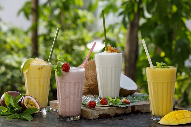Vier verschillende soorten smoothies op een rij. Van links naar rechts. Passievrucht, aardbei, kokos en mango smoothies. Allemaal in een glas met een rietje.